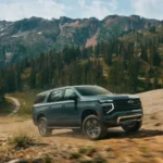 2025 Chevrolet Suburban màu tối đang chạy off-road, chụp góc 3/4 phía trước.