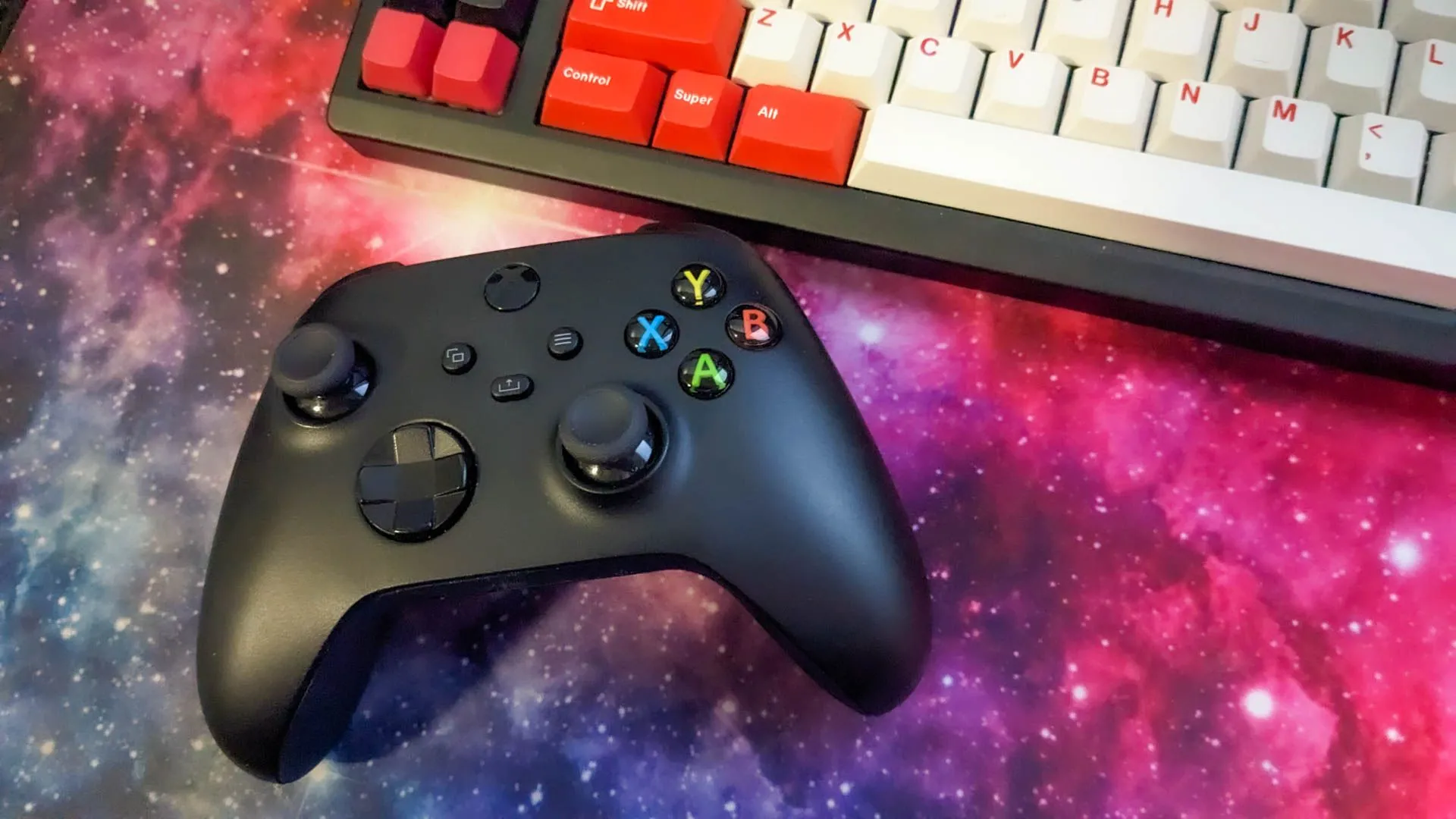Bộ tay cầm Xbox đặt cạnh bàn phím cơ và miếng lót chuột lớn