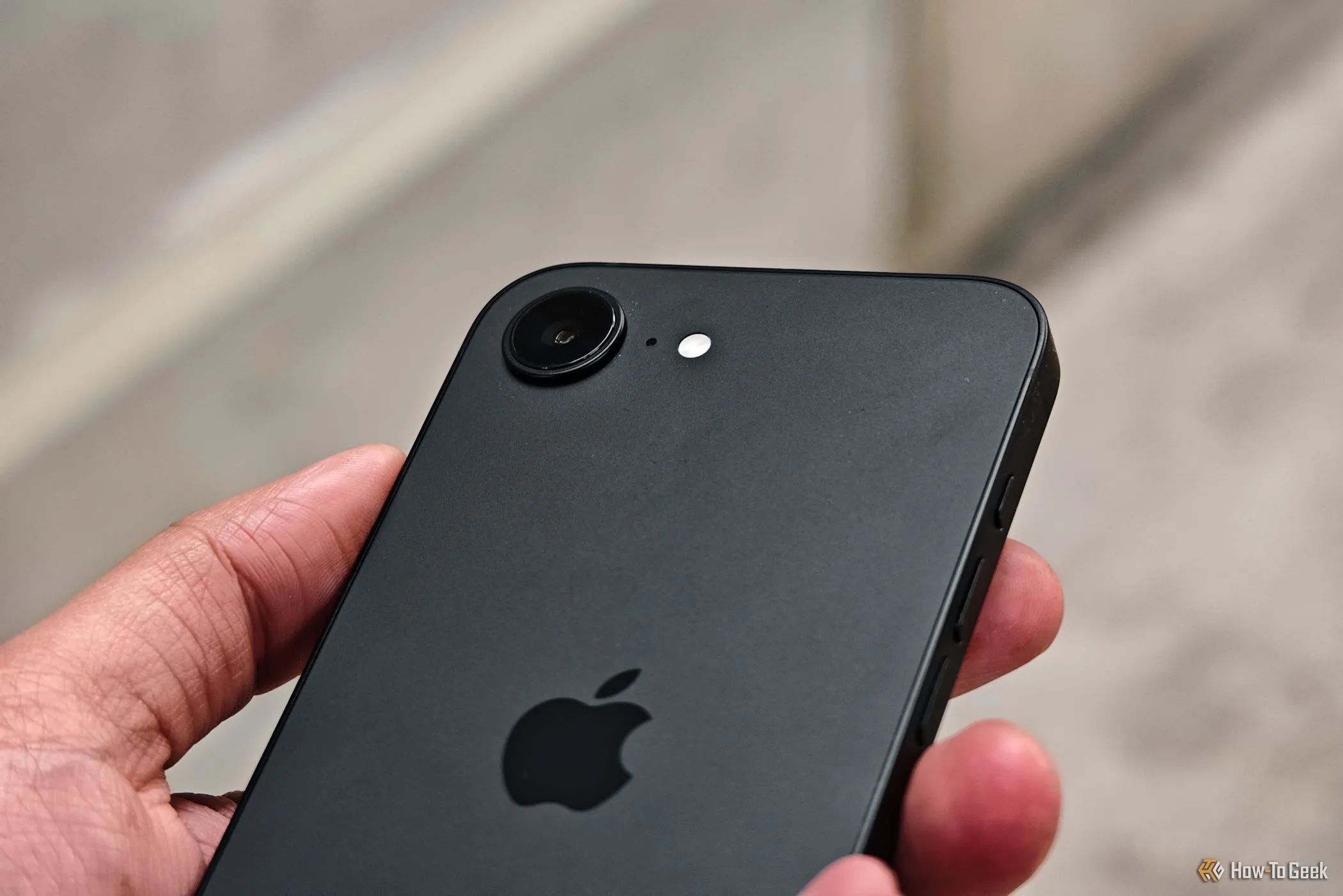 Cận cảnh cụm camera đơn 48MP của iPhone 16e được cầm trong tay, thể hiện thiết kế tối giản