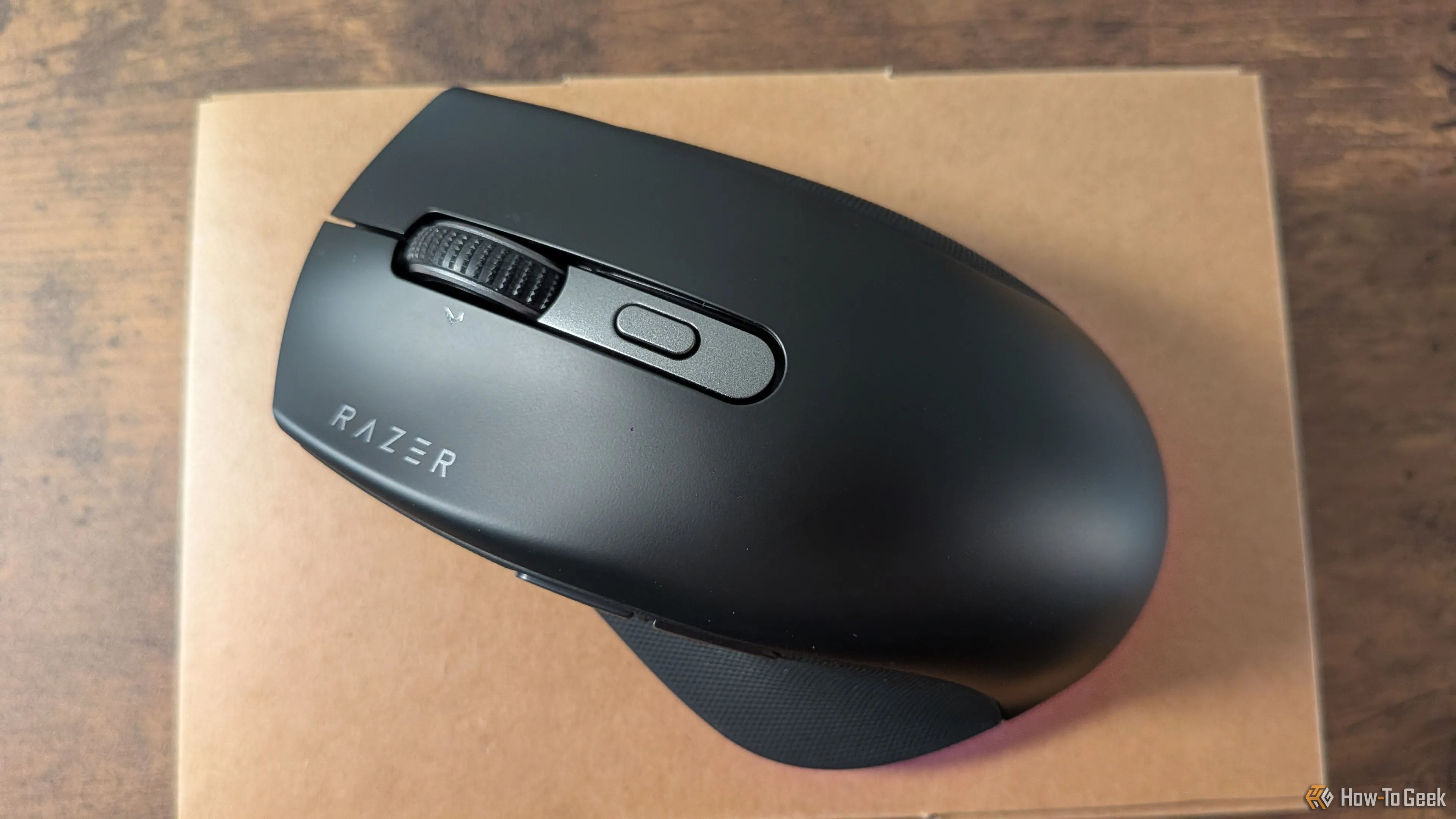 Chuột Razer Pro Click V2 với đèn LED phát sáng, đặt trên hộp sản phẩm, minh họa khả năng chiếu sáng tinh tế của thiết bị.