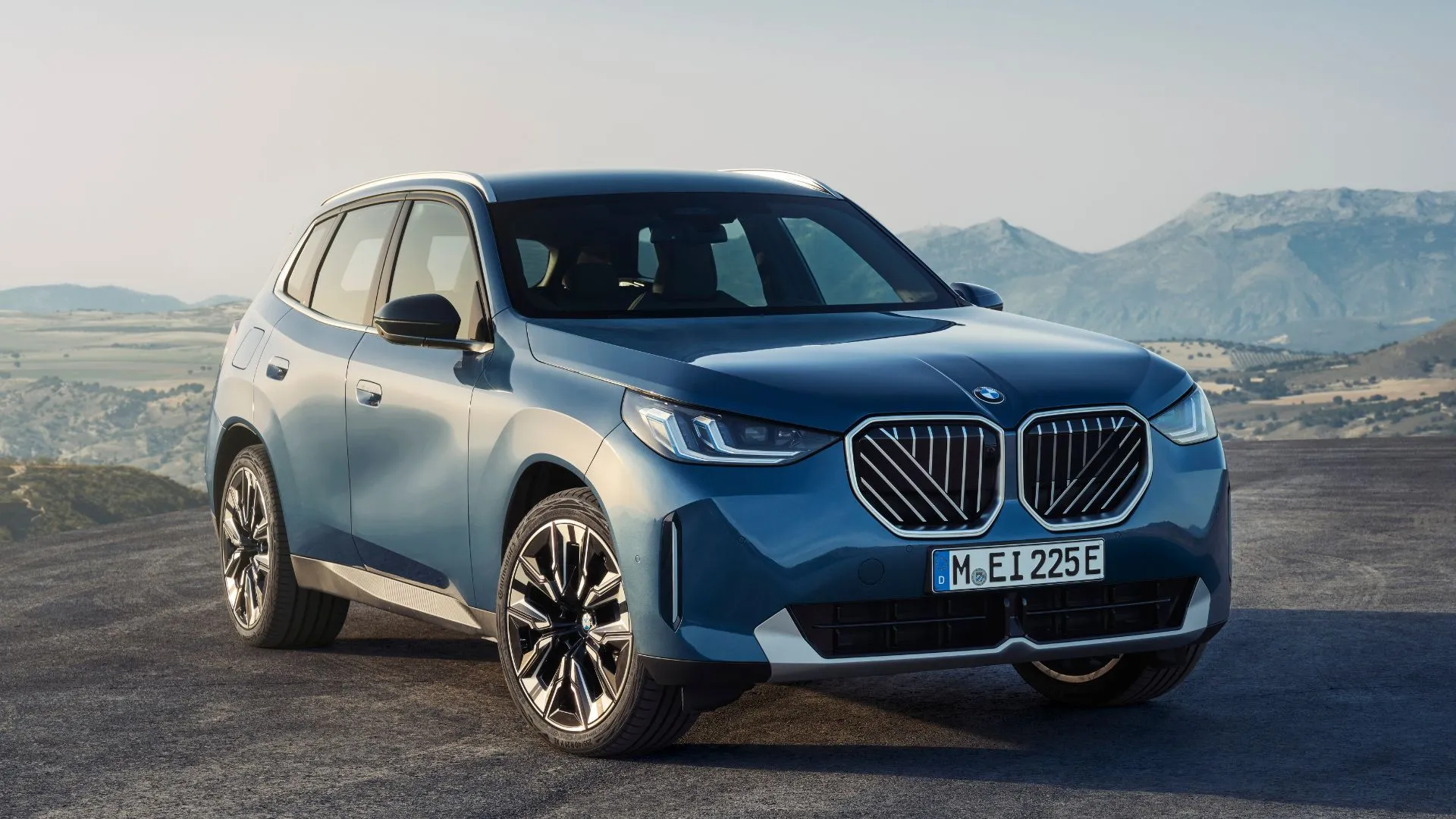 Hình ảnh cận cảnh phía trước của xe BMW X3 2025 màu xanh đậu trên nền sỏi.