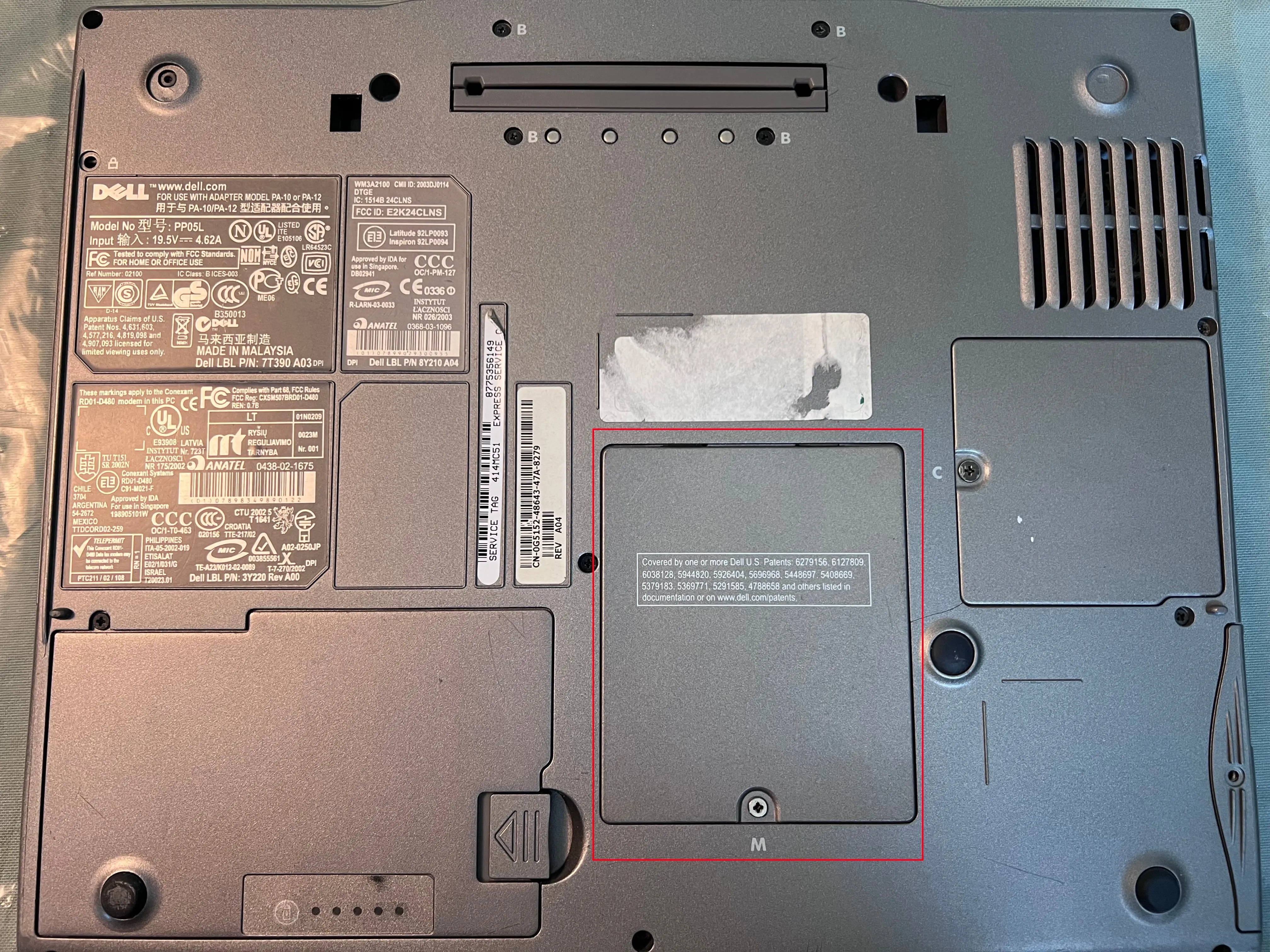 Hình ảnh mặt dưới laptop Dell với nắp đậy khe RAM được đánh dấu màu đỏ, hướng dẫn tháo lắp.