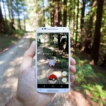 Hình ảnh người chơi tương tác với game Pokémon GO trên điện thoại, minh họa công nghệ thực tế tăng cường (AR) và định vị GPS trong game mobile.