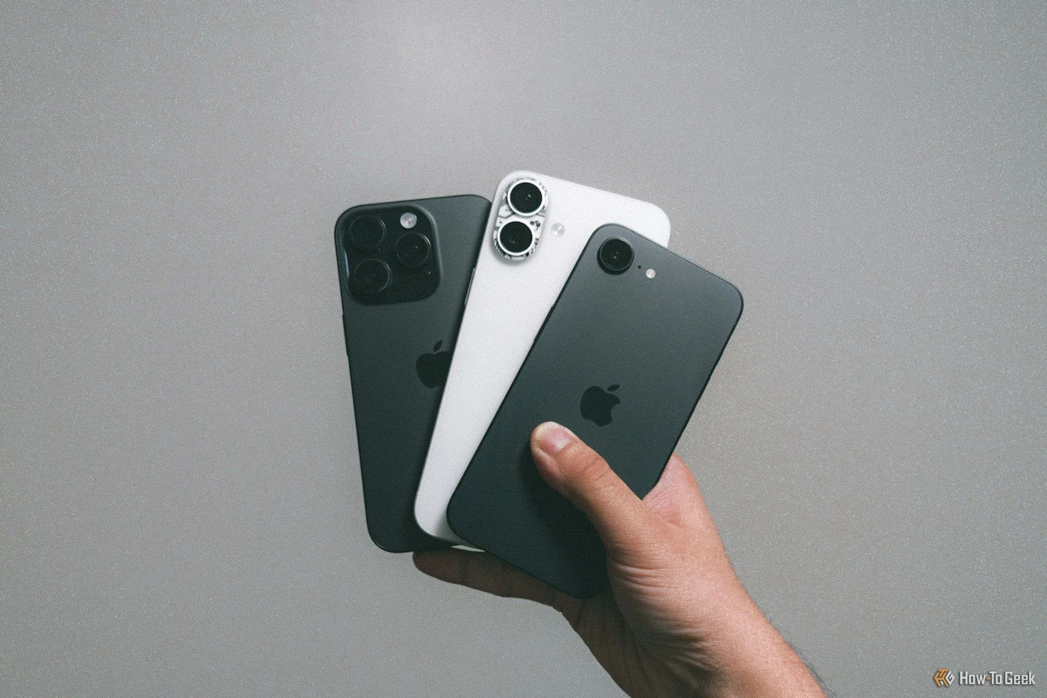 Hình ảnh so sánh kích thước và thiết kế của iPhone 16e (trái), iPhone 16 Plus (giữa) và iPhone 16 Pro (phải) được cầm trong tay