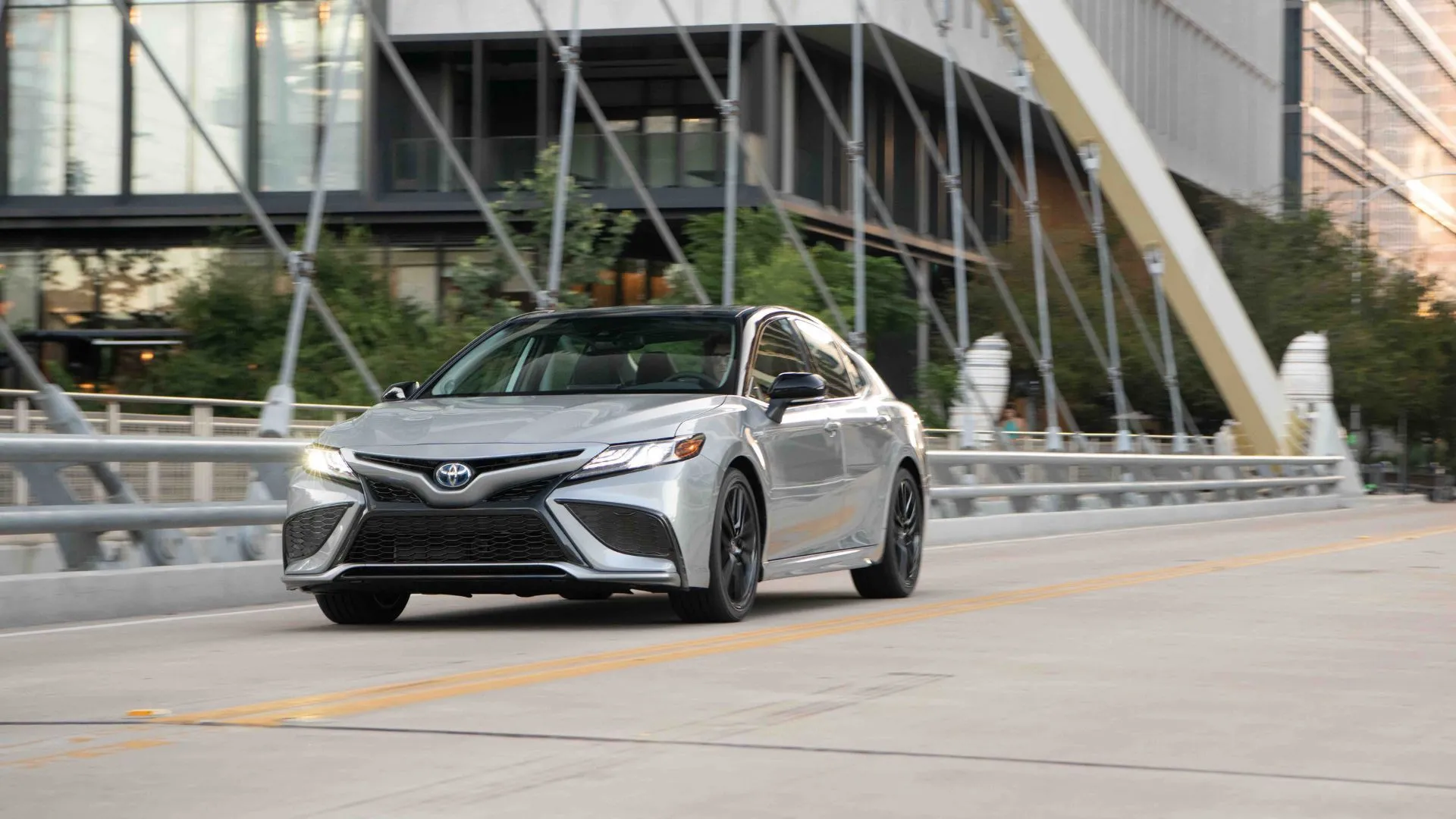 Hình ảnh xe Toyota Camry Hybrid di chuyển trong thành phố, biểu tượng của sự thích nghi với thị trường ô tô.
