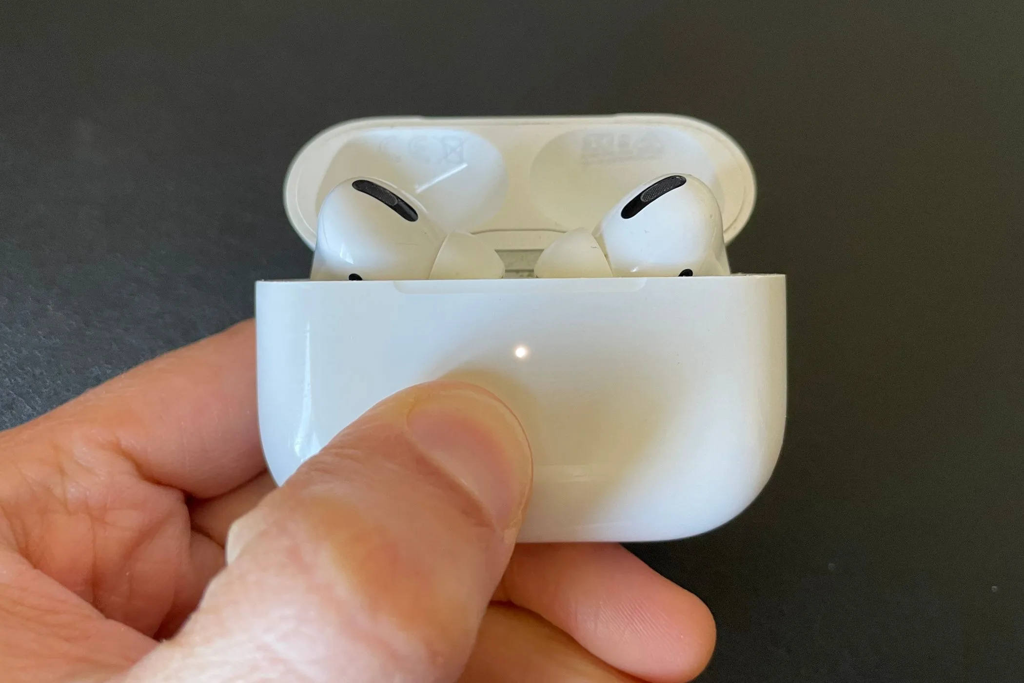 Hộp sạc AirPods Pro với tai nghe bên trong và đèn trạng thái màu trắng báo hiệu pin.