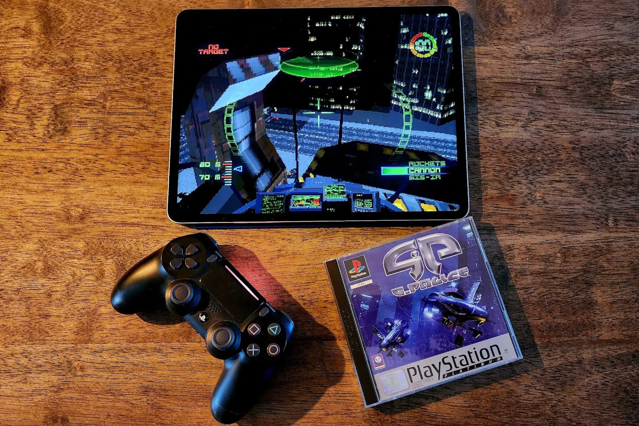 iPad chạy game G-Police đặt cạnh đĩa game PS1 gốc và tay cầm PS4