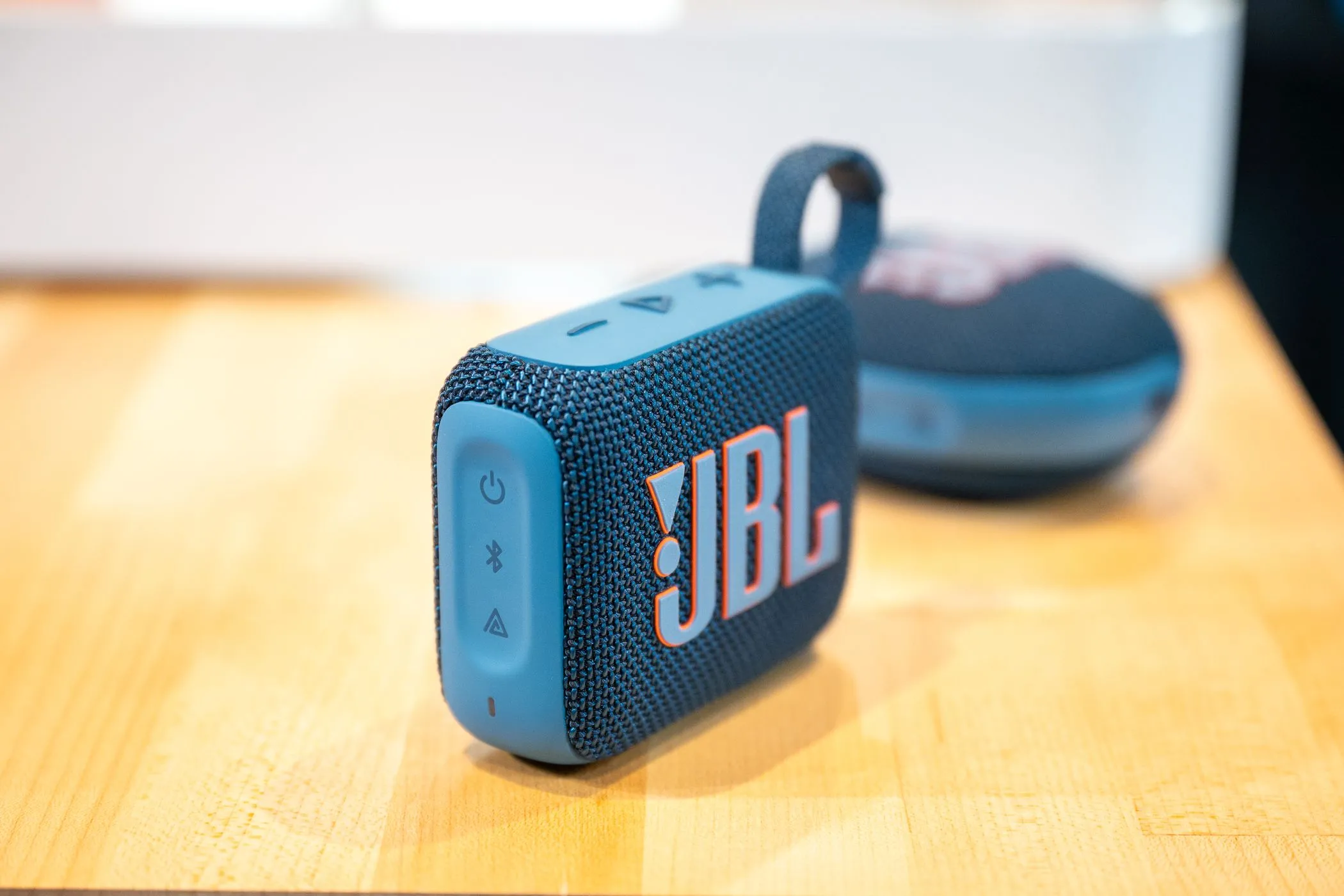 Loa Bluetooth di động JBL Go 4 đặt trên bàn, phía trước là JBL Clip 5, lý tưởng cho âm nhạc khi đi du lịch.