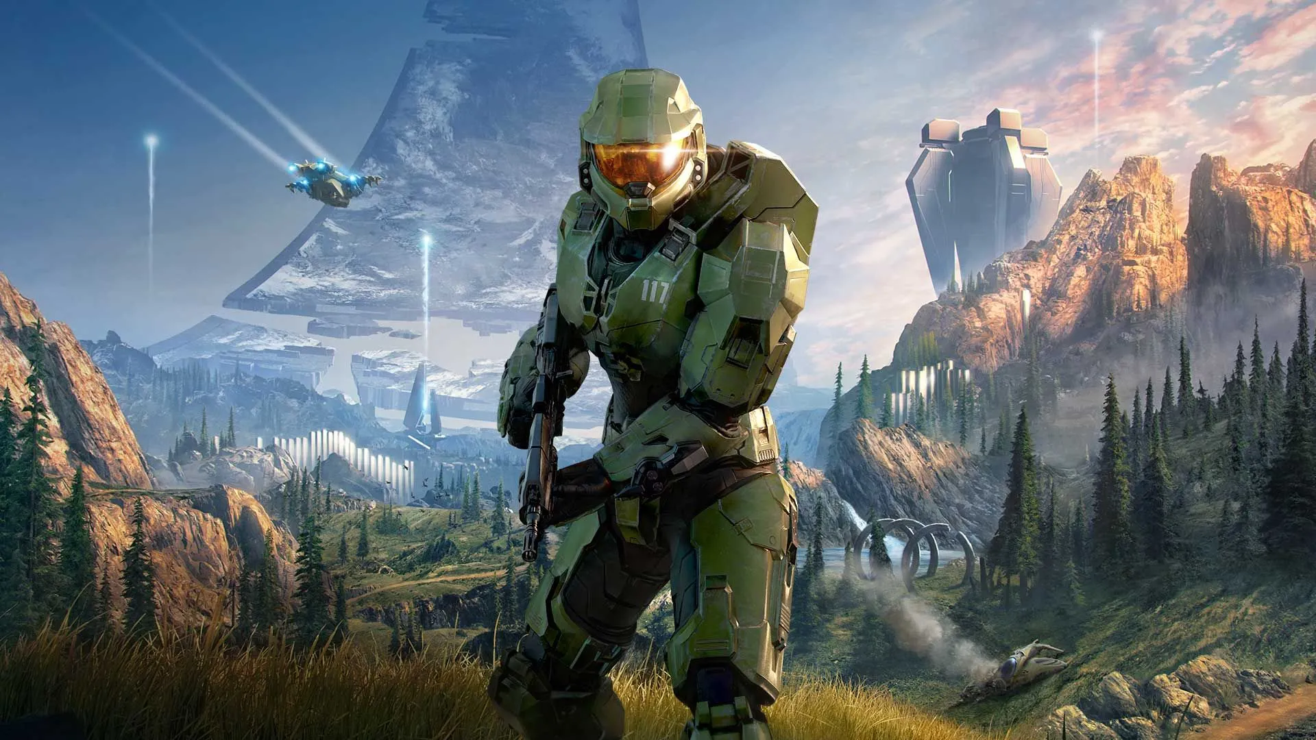 Master Chief cầm vũ khí trong khu vực cỏ và rừng trên vành đai Halo Infinite.