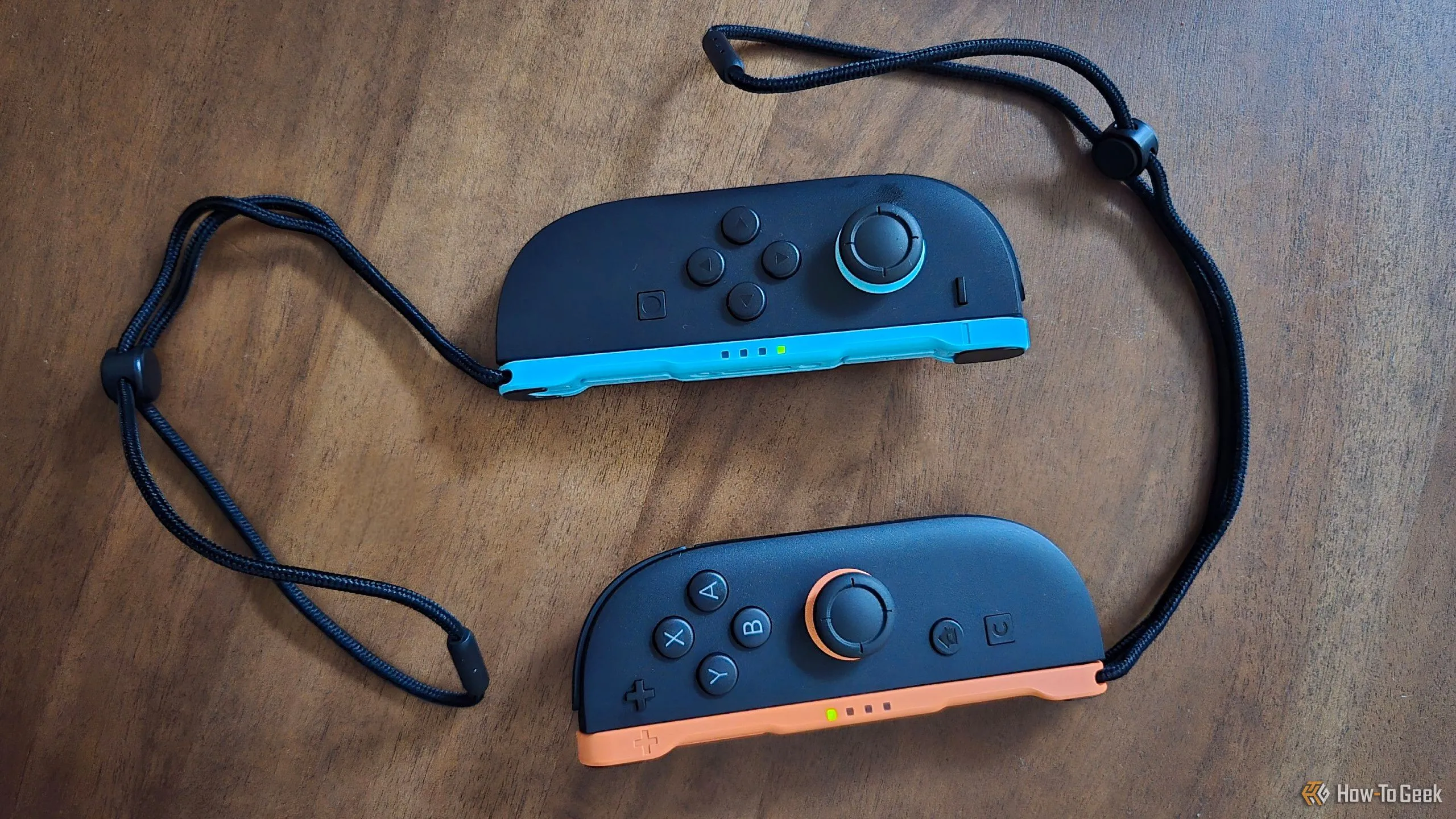 Một cặp tay cầm Joy-Con 2 kèm dây đeo cổ tay, cho thấy sự cải tiến về kích thước và cảm giác cầm nắm.