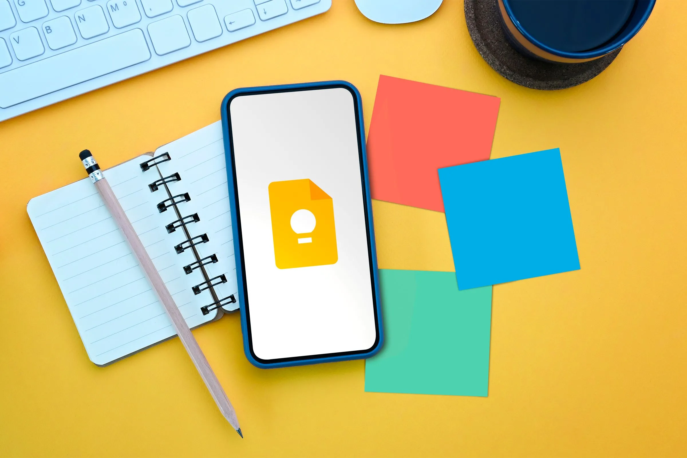 Một chiếc điện thoại hiển thị logo Google Keep Notes nằm trên quyển sổ, xung quanh là các ghi chú dán, minh họa khả năng ghi chú linh hoạt.