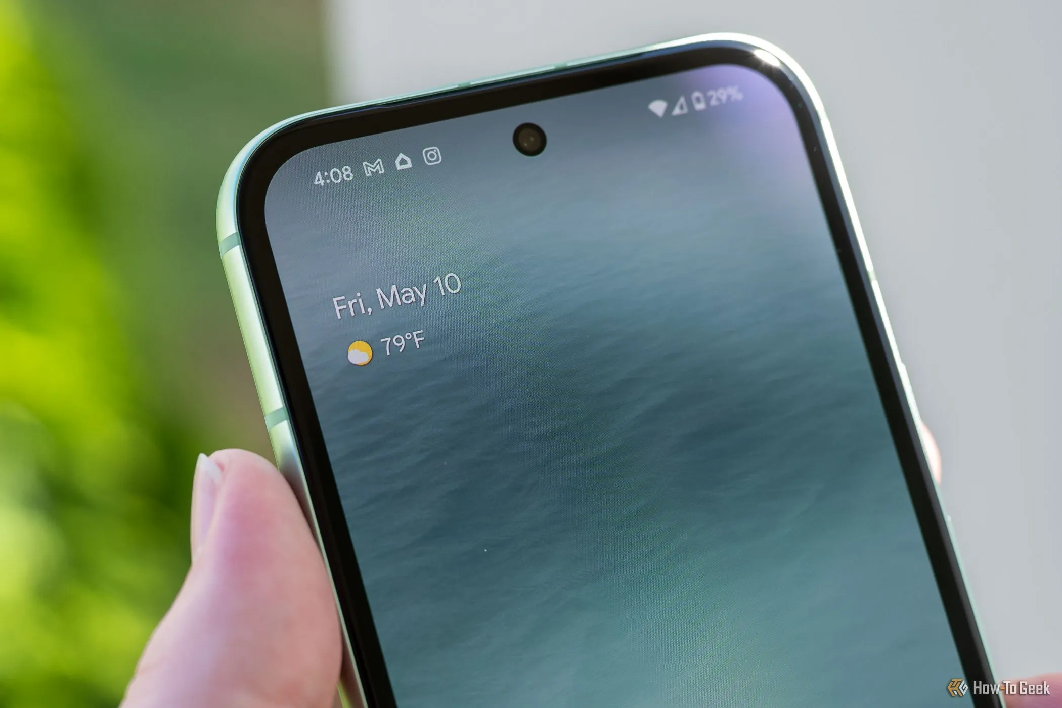 Một người cầm điện thoại Google Pixel 8a hiển thị camera trước và màn hình, thể hiện thiết kế màn hình đục lỗ và viền màn hình tổng thể.