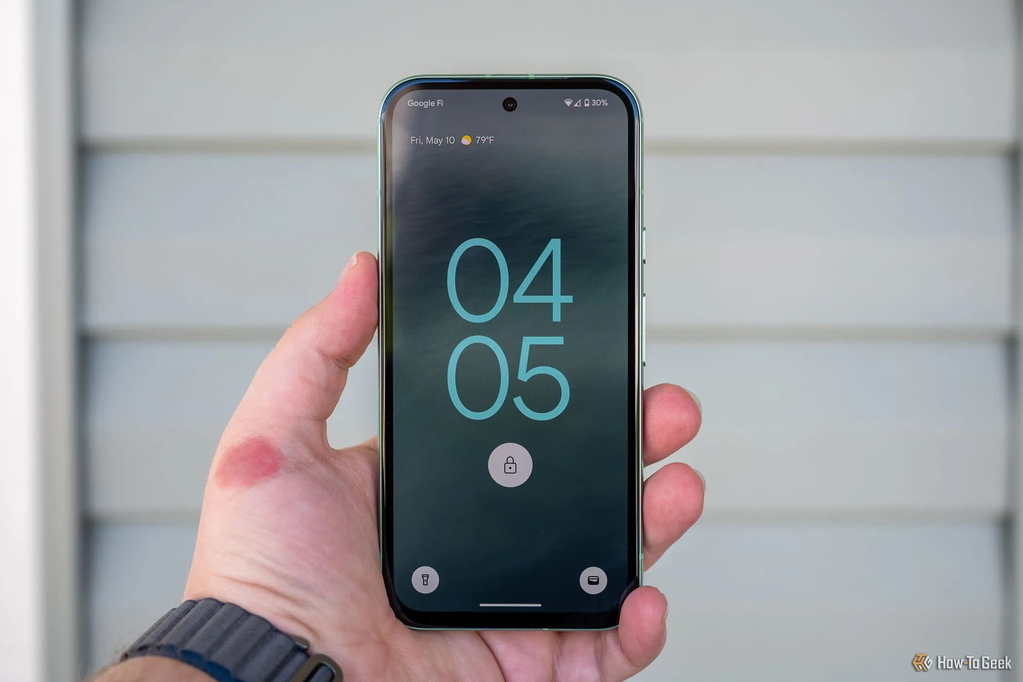 Một người cầm điện thoại Google Pixel 8a hiển thị màn hình khóa, tượng trưng cho khả năng cập nhật phần mềm lâu dài và trải nghiệm người dùng Android hiện đại.