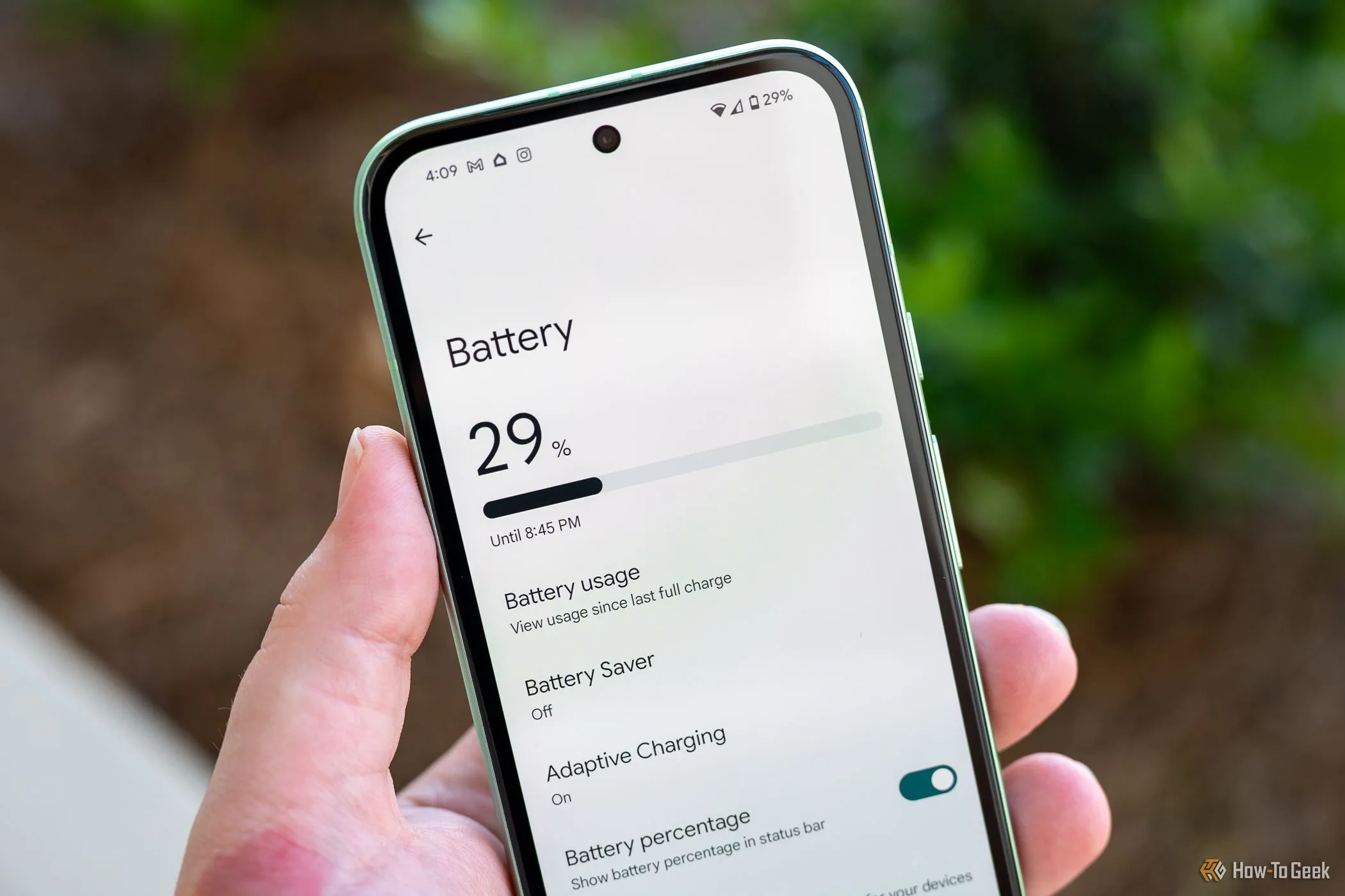 Một người đang cầm điện thoại Google Pixel 8a hiển thị menu cài đặt pin, với biểu tượng phần trăm pin lớn, cho thấy tình trạng pin của thiết bị.