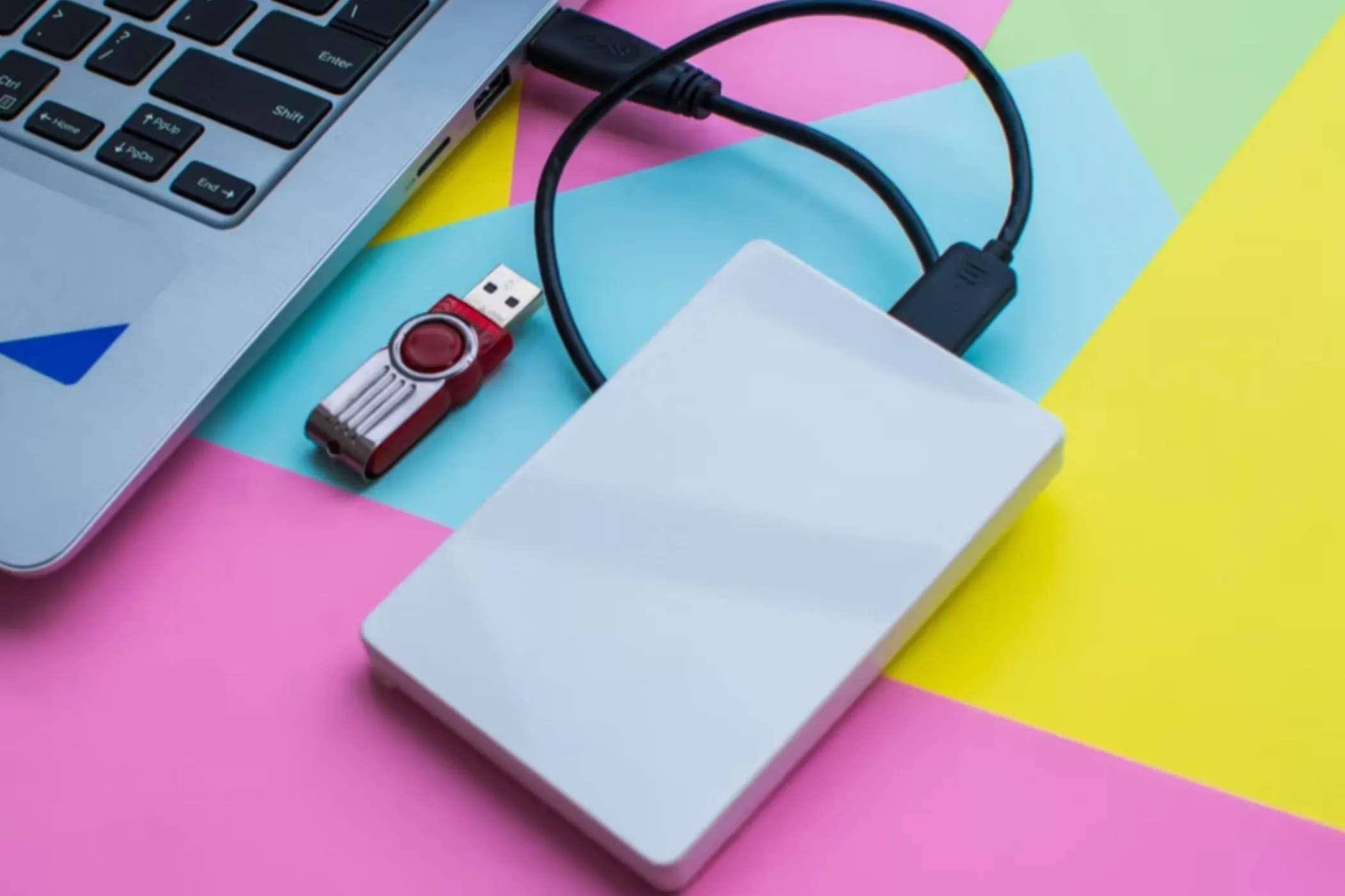 Một USB flash drive và một ổ cứng gắn ngoài được kết nối với máy tính xách tay, thể hiện việc chuyển dữ liệu nhạc giữa các thiết bị.