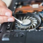 Người đang vệ sinh bàn phím laptop bằng tăm bông để loại bỏ bụi bẩn