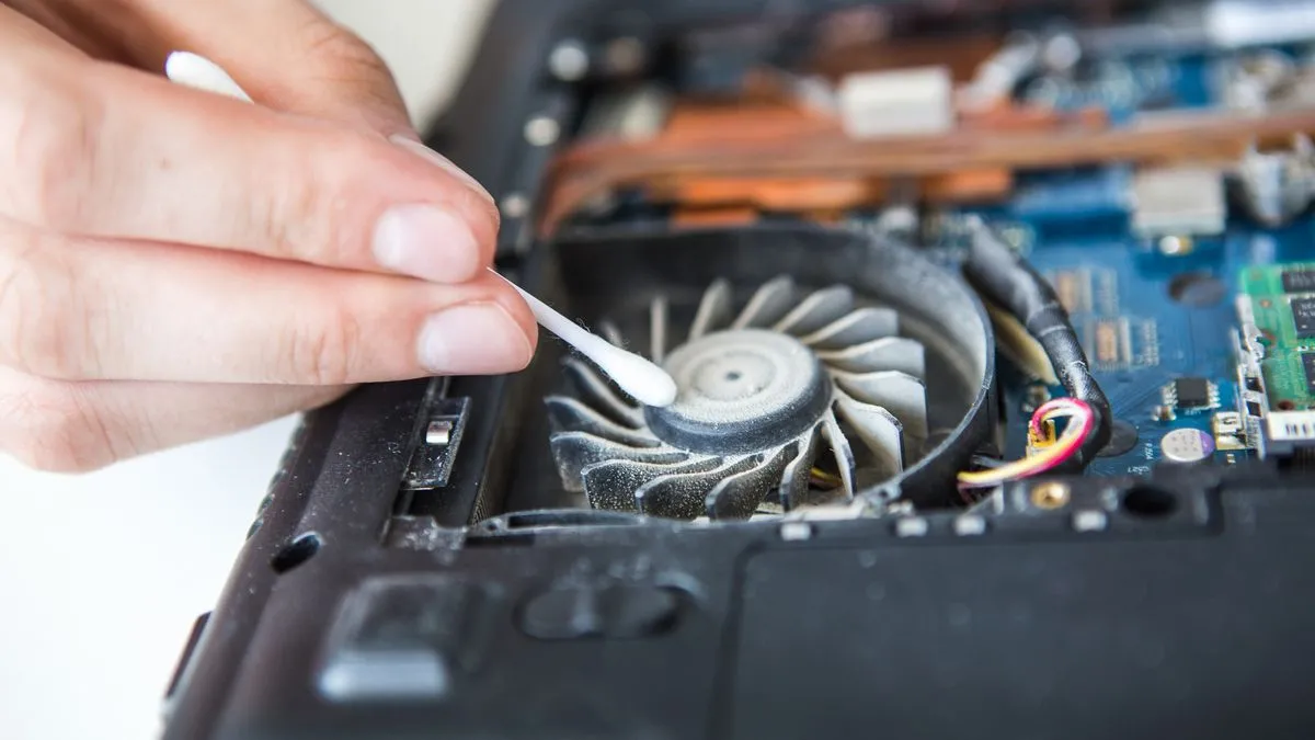 Người đang vệ sinh bàn phím laptop bằng tăm bông để loại bỏ bụi bẩn