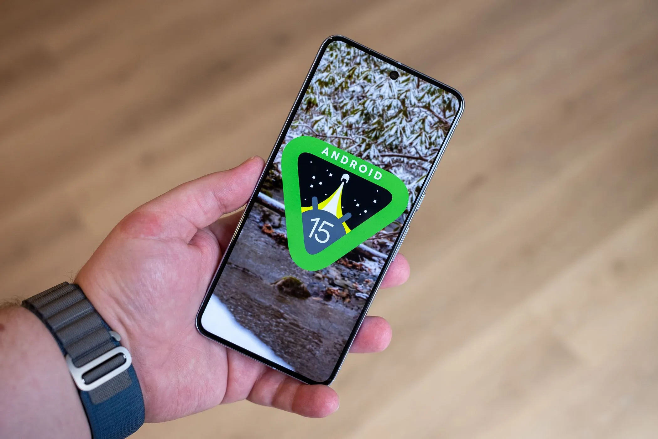 Người dùng cầm điện thoại Google Pixel 8 Pro với màn hình hiển thị logo Android 15, minh họa chính sách cập nhật phần mềm điện thoại Android dài hạn.
