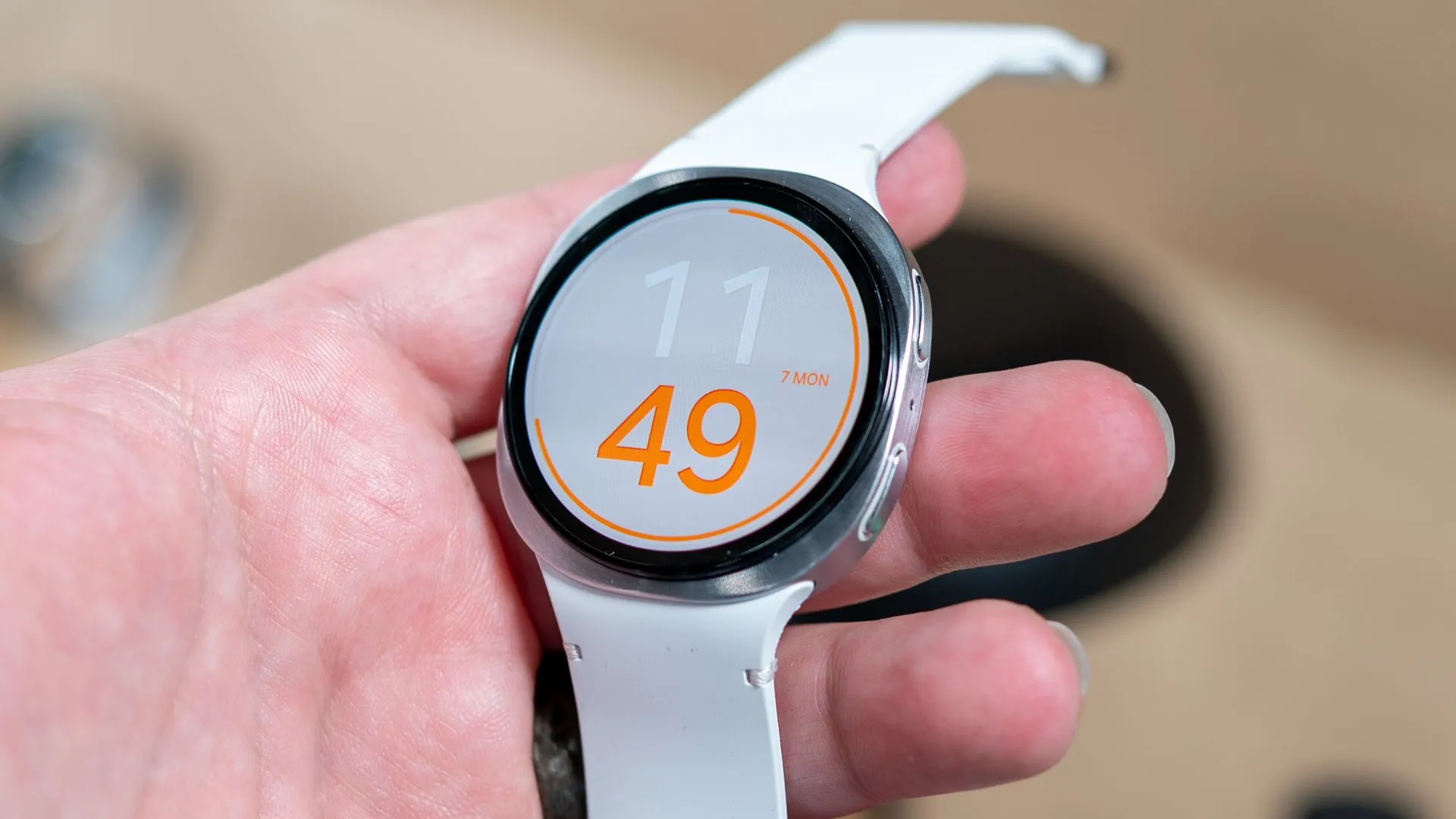 Người dùng đang cầm chiếc Samsung Galaxy Watch 8 phiên bản tiêu chuẩn với thiết kế viền cảm ứng và mặt vuông bo tròn.