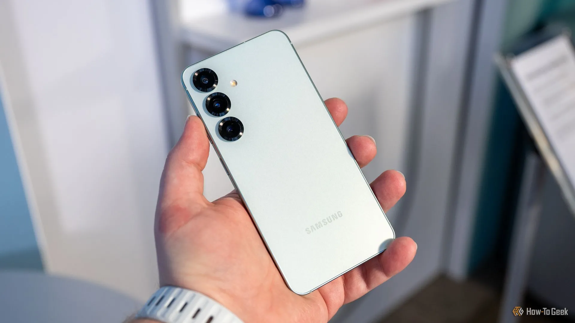 Người dùng đang cầm Samsung Galaxy S25 và nhìn vào cụm camera sau.