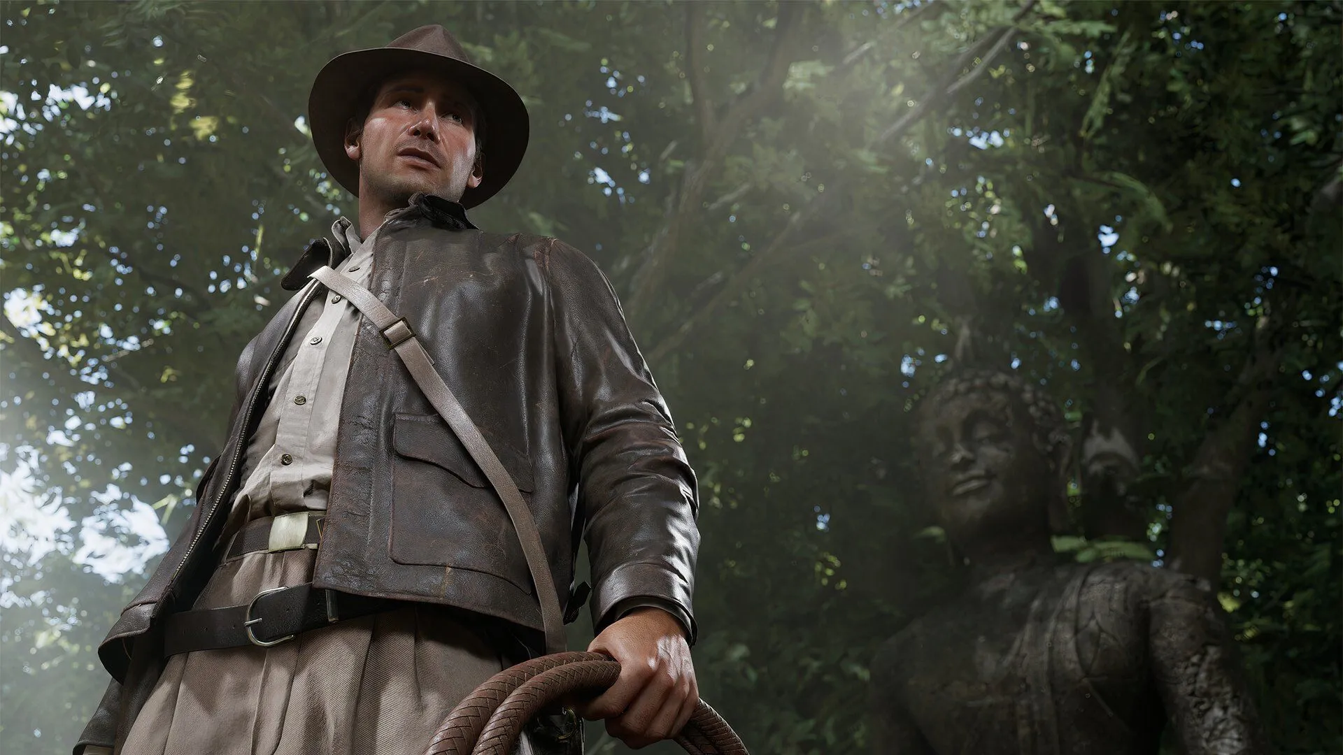 Nhân vật Indiana Jones đứng cạnh một bức tượng cổ trong game Indiana Jones and the Great Circle, biểu tượng cho tinh thần phiêu lưu và khám phá trong loạt phim huyền thoại.