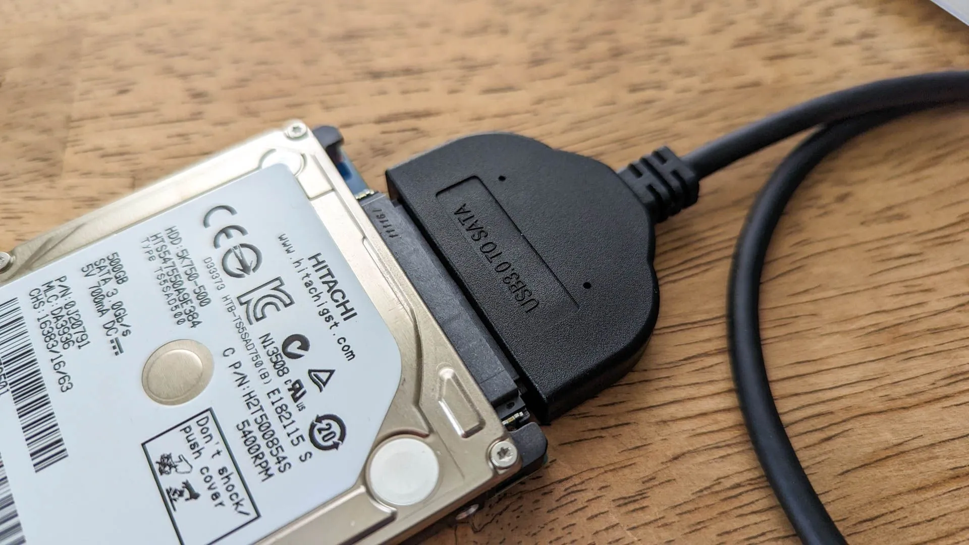Ổ cứng laptop cũ đang được kết nối với bộ chuyển đổi USB sang SATA để kiểm tra hoặc sao lưu dữ liệu.