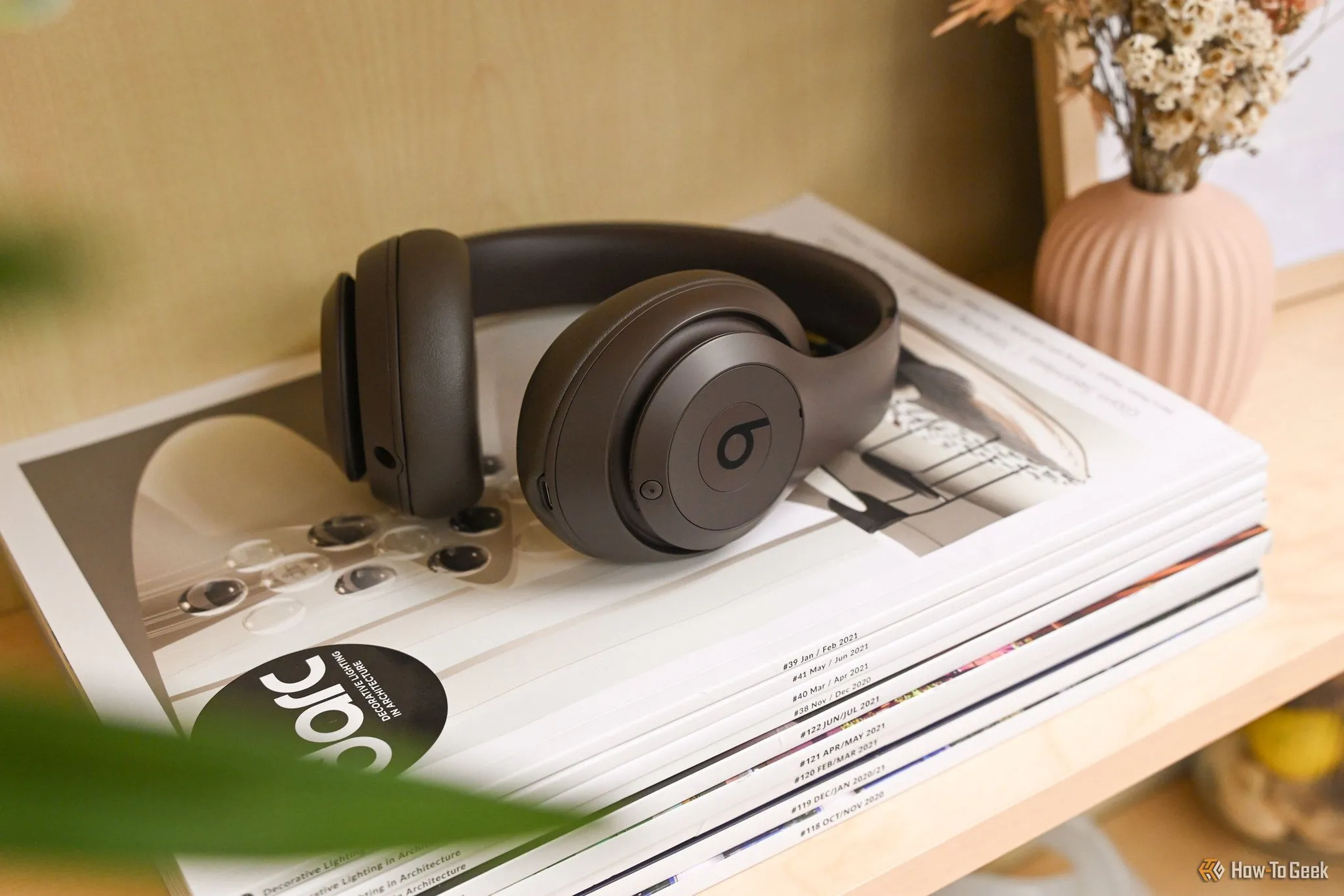 Tai nghe Beats Studio Pro màu nâu sang trọng đặt trên các tạp chí, biểu tượng cho các ưu đãi công nghệ hấp dẫn khác.