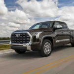 Xe bán tải Toyota Tundra 2025 màu nâu đất chạy trên đường cao tốc.